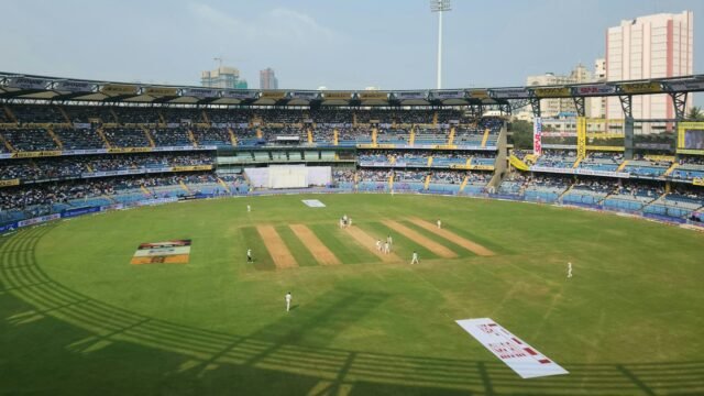 A cricket stadium in daylight with a crowd in the stands
