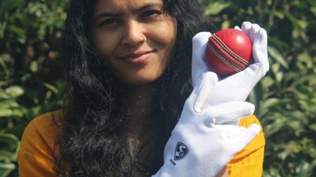A woman cricketer holding a red cricket ball