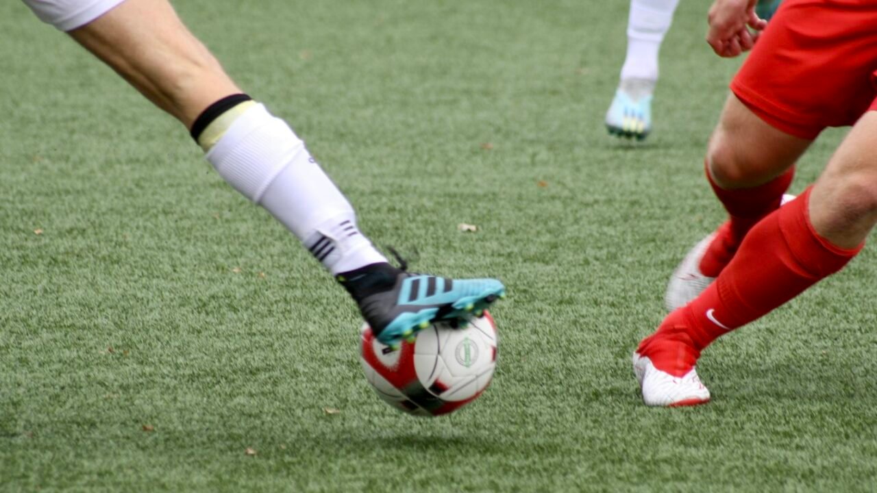 Close-up of football boots and a ball on the pitch