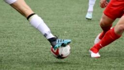 Close-up of football boots and a ball on the pitch