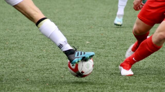Close-up of football boots and a ball on the pitch