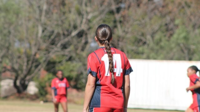 A woman cricketer in red fielding during a match