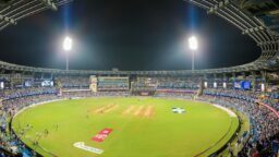 A cricket stadium full of spectators at night