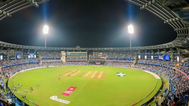 A cricket stadium full of spectators at night
