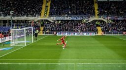 A footballer on a stadium pitch with the goal behind